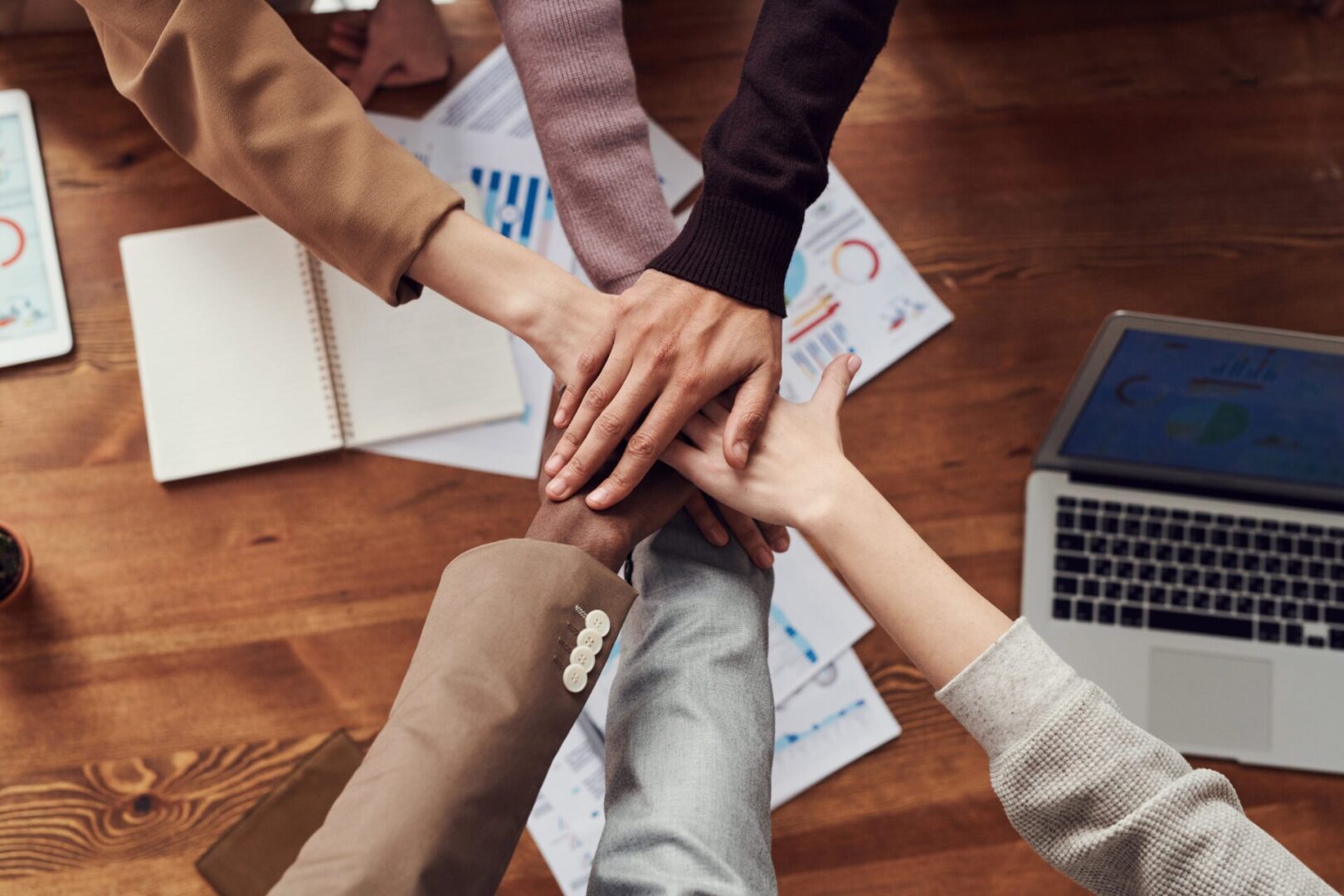 A group of people holding hands on top of papers.